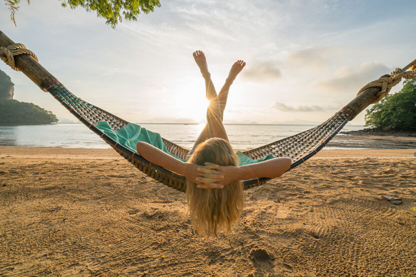 Young woman relaxing on hammock by the beach, sunrise- Thailand